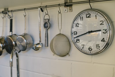 圆形白色和灰色不锈钢模拟时钟显示02:43时间接近灰色不锈钢平底锅挂在墙上
